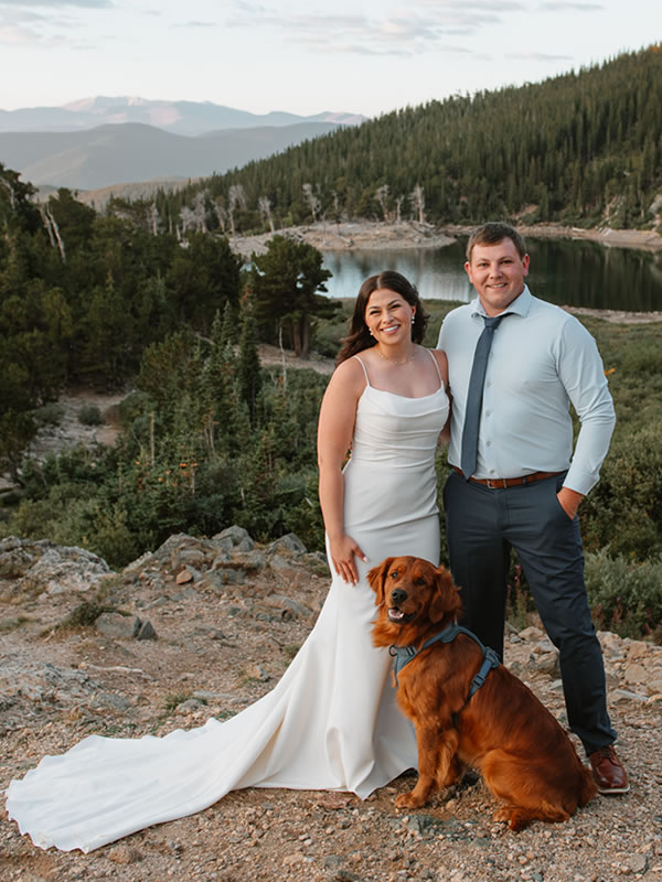 A bride and groom with their golden retriever beside an alpine lake in the Colorado mountains