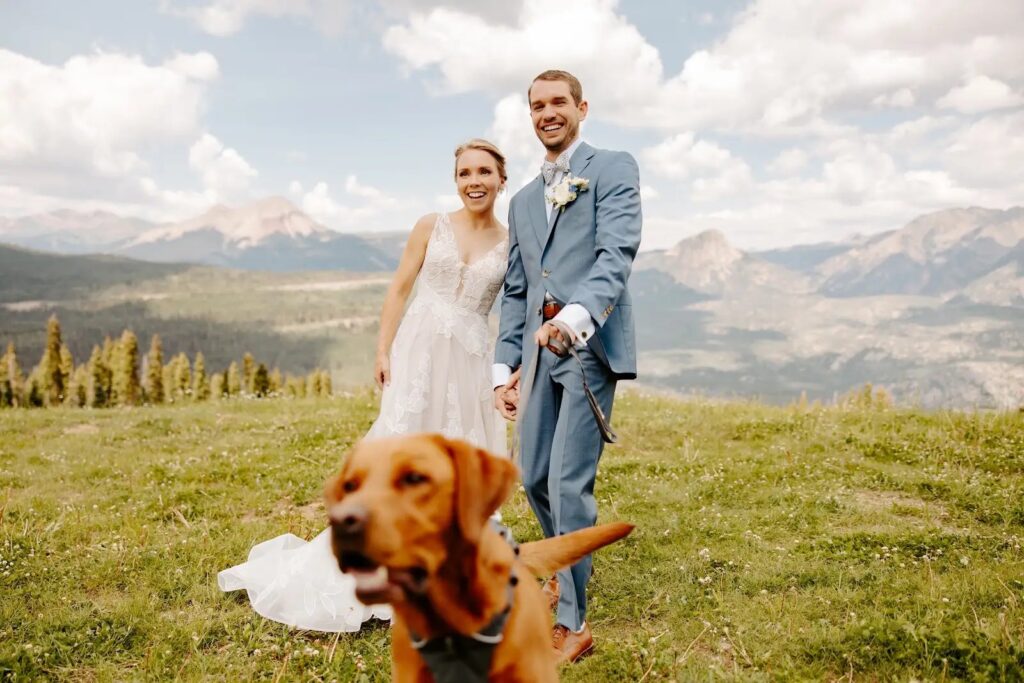 Bride hugging her dog with mountain peaks behind them